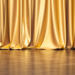Elegant gold curtains on stage, symbolizing the prestigious RBC Canadian Women Entrepreneur Award nomination for Jayne's Luxury Rentals