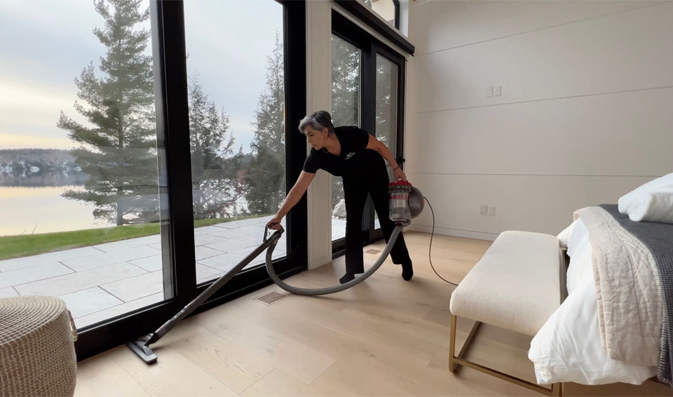 Housekeeping staff vacuuming with a scenic lake view at a Jayne's Luxury Rentals property