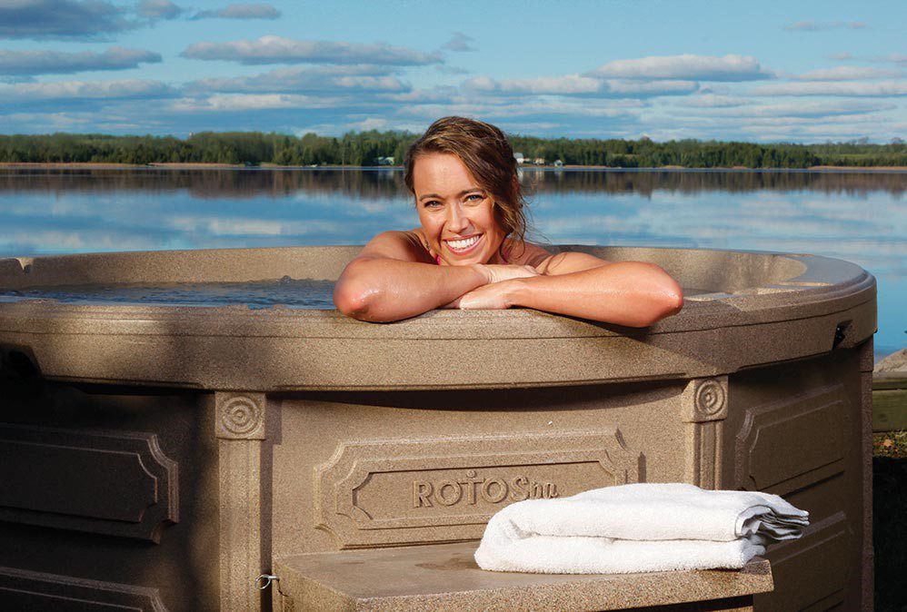 Guest relaxing in a lakeside hot tub rental enjoying the serene lake view - Jayne's Luxury Rentals