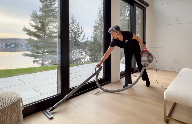 Housekeeping staff vacuuming with a scenic lake view at a Jayne's Luxury Rentals property