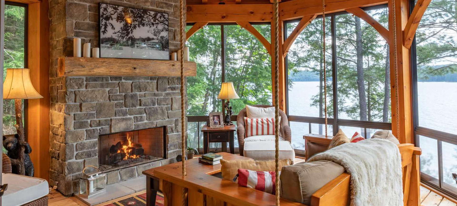 Primrose Property in Huntsville - Jayne's Luxurious Rentals | Cozy lakeside living room with stone fireplace and panoramic views
