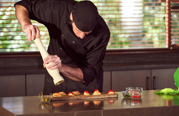 Private Chef service at Jayne's Luxurious Rentals | Chef skillfully adding a finishing touch to gourmet dishes
