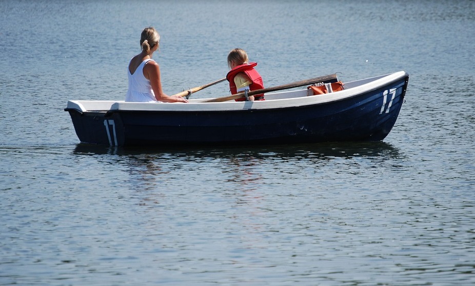 Mother and child enjoying a peaceful rowboat ride on a serene lake - Jayne's Luxury Rentals