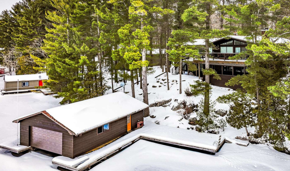 Property Services at Jayne's Luxurious Rentals | Aerial view of a cozy cabin retreat surrounded by a winter woodland