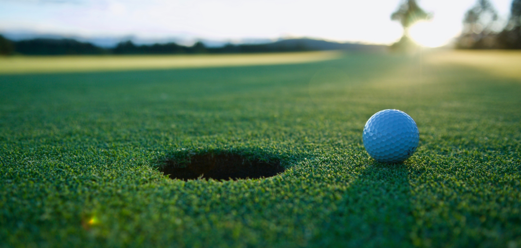 Sunset Golfing Experience at Jayne's Luxurious Rentals | Close-up of a golf ball near the hole on a lush course.