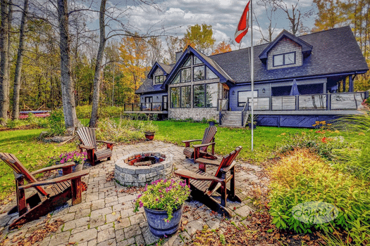 Deerview property in Huntsville - Jayne's Luxurious Rentals | Inviting fire pit area with Adirondack chairs set in a lush landscape