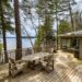 Camp Muskoka's lake-view deck in Muskoka Lakes - Jayne's Luxurious Rentals | A serene spot with outdoor seating surrounded by towering pines