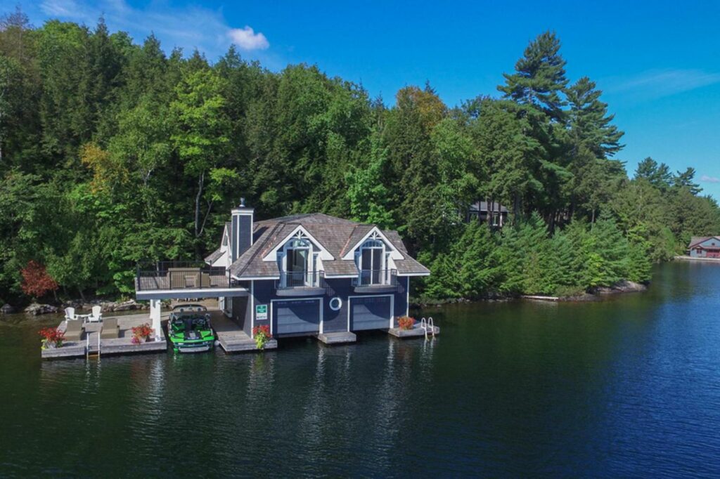 Aerial view of Jayne's Luxurious Property's lakeside house with a private dock and boat on a sunny day, surrounded by lush greenery