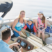 A family shares a joyful moment on a boat ride offered by Jayne's Luxury Rentals, with clear skies overhead