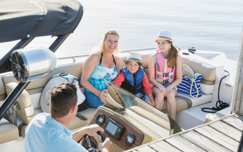 A family shares a joyful moment on a boat ride offered by Jayne's Luxury Rentals, with clear skies overhead