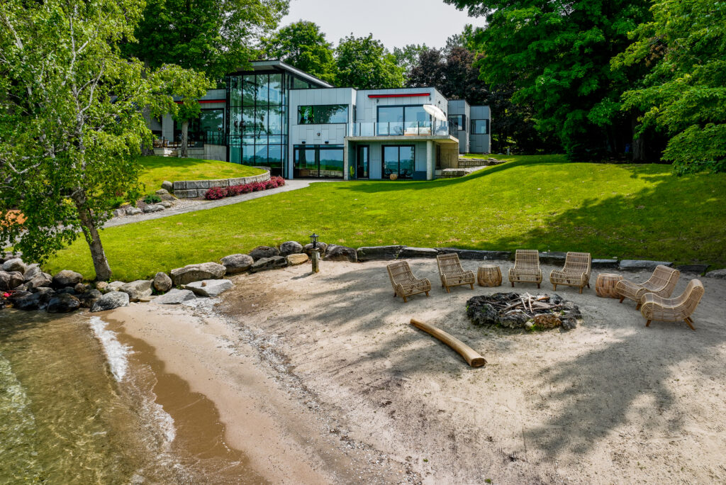Private beach and firepit area at Boca North property with modern glass facade, located in Barrie South - Jayne's Luxury Rentals