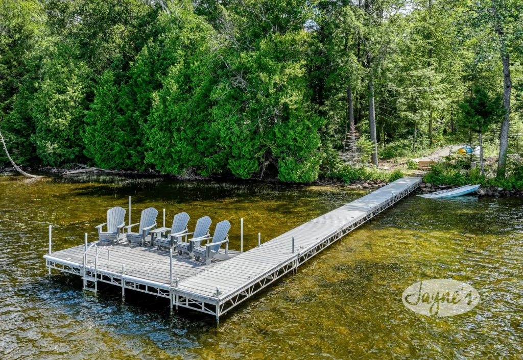 Tranquil Formosa Pines waterfront with a long, inviting dock lined with Adirondack chairs, beckoning for a leisurely day by the lake at Jayne's Luxury Rentals.