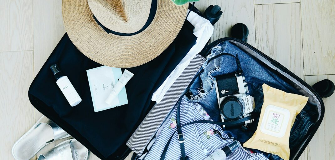 Open suitcase packed with travel essentials including camera, clothes, and toiletries, ready for a luxurious vacation - Jayne's Luxurious Rentals Blog.