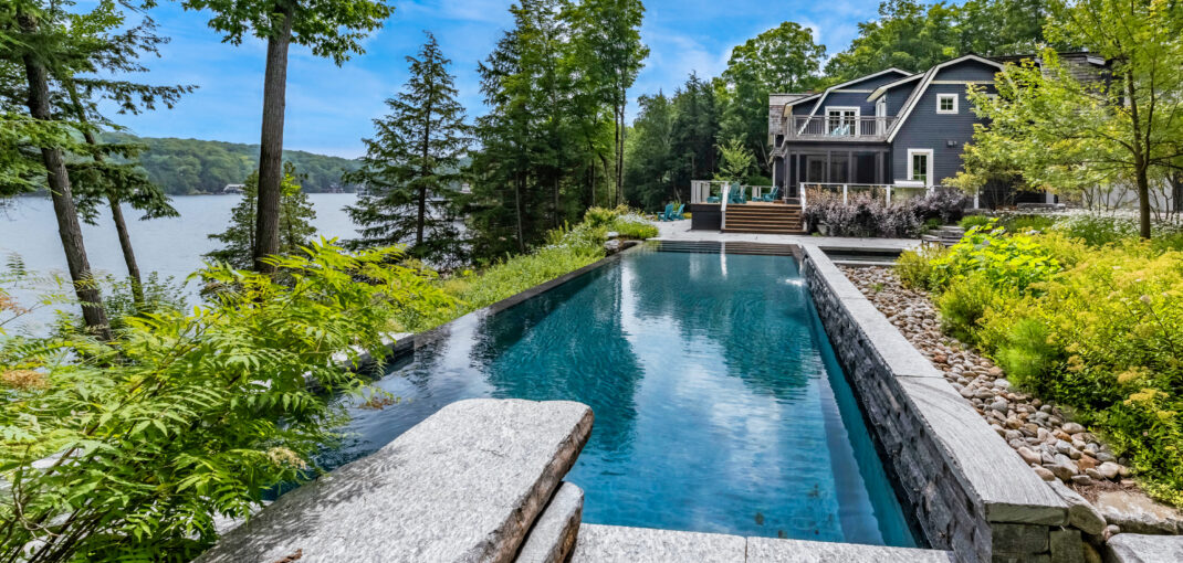Peaceful waterside infinity pool extending into Lake Joseph at Avonlee, exclusively by Jayne's Luxury Rentals.